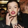 Rote Lippen sind an Feiertagen besonders gefragt. Frau mit roten Lippen, großen Ohrringen und roten Nägeln.