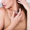Immer mehr Frauen tragen extra fürs Training ein Parfum auf, um sich selbstbewusster zu fühlen. Eine Frau hält eine Parfumflasche nah an ihren Hals und guckt seitlich nach unten.