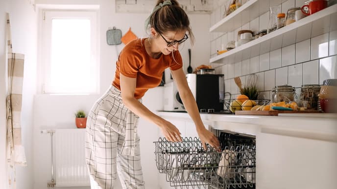 Küche sauber halten 3 Tricks Junge Frau räumt Geschirrspülmaschine ein
