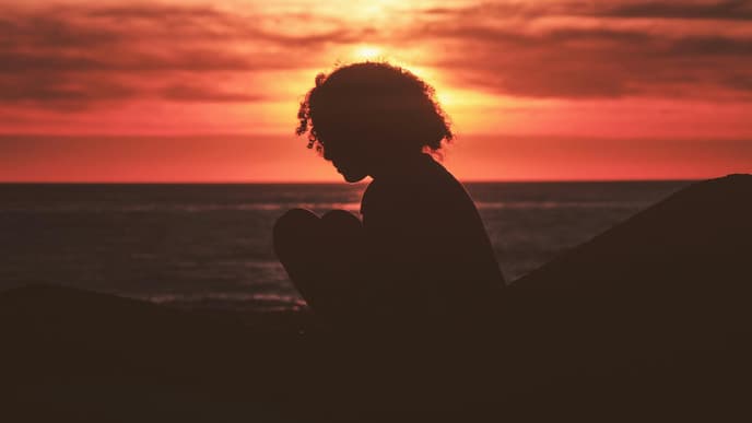 Pech-Sternzeichen der Woche Frau sitzt beim Sonnenuntergang am Meer