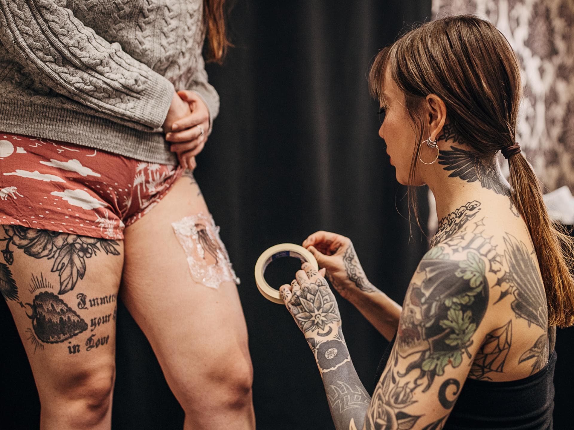 Tattoo Folie entfernen: Das ist der richtige Zeitpunkt um mit der Tattoo-Pflege zu starten Tätowiererin foliert frisches Tattoo